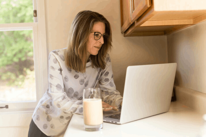 woman with blond hair using white MacBook Pro inside white room