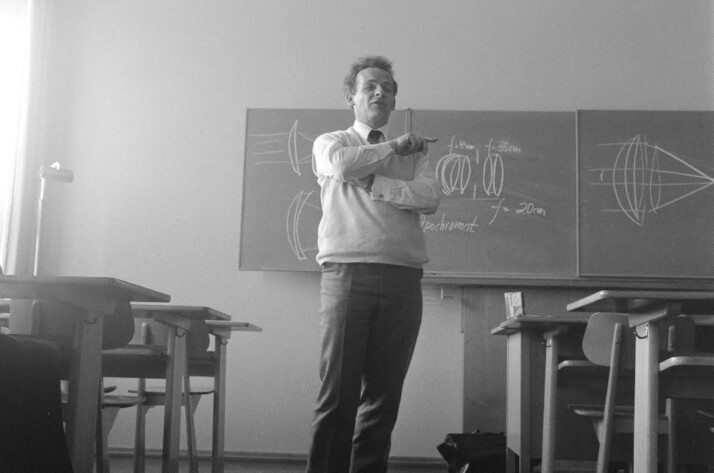 A black and white photo of a professor standing in front of a black board.