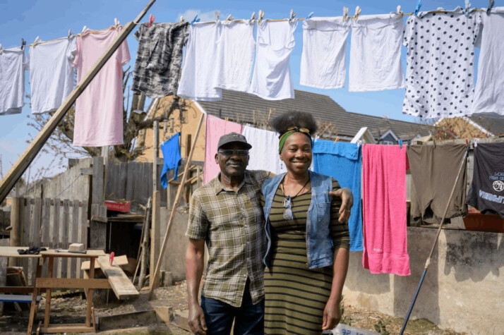 a black couple standing in their garden near a clothes line.