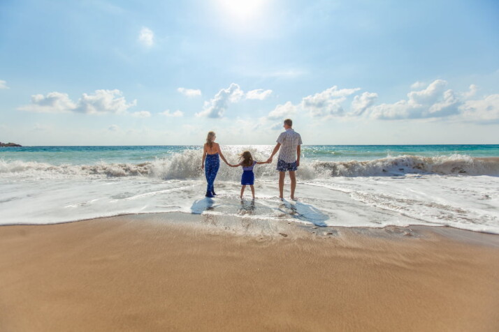 Parents holding their daughter on a beautiful and sunny beach.