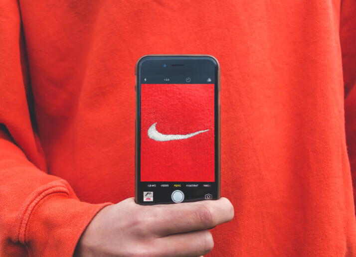 person holding iphone taking picture of nike label of a red jumper