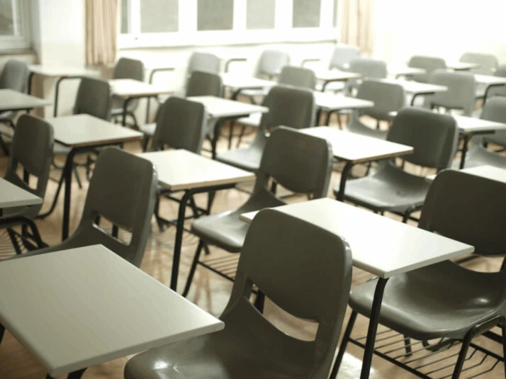 An image of a classroom with white table with black chairs