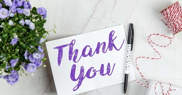 black pen and thank you note on white table near flowers