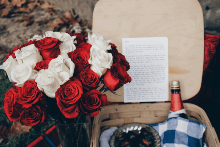 Red and white roses beside a beige wicker basket