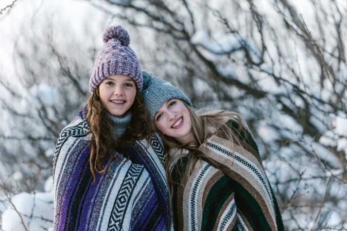 Two sisters wearing winter clothes and smiling on the camera