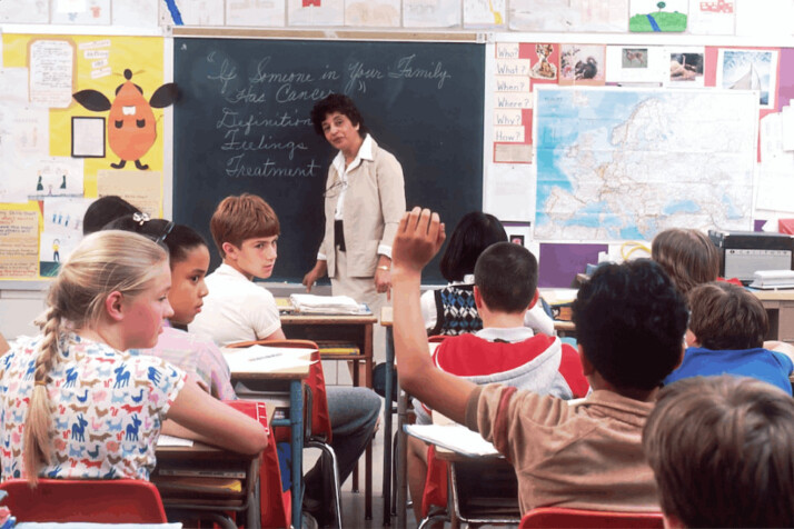 a short haired woman teacher in front of the blackboard in class.