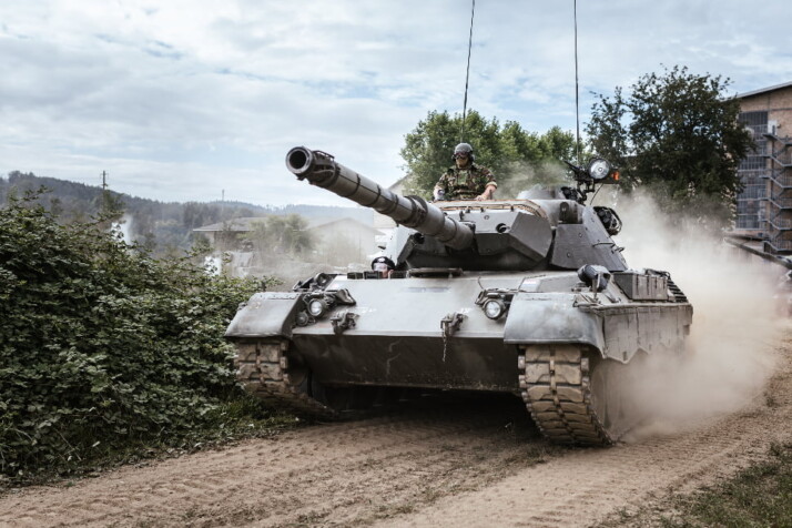 A soldier sitting on top of a war tank.