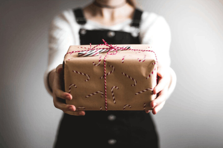 A person showing brown gift box and offering it