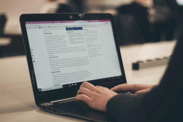 a person wearing a black sweater typing on laptop computer