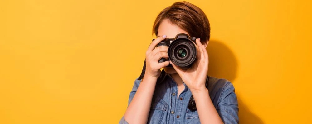 woman with brown hair and wearing blue jacket using camera