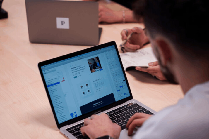 person wearing white shirt using macbook pro on table