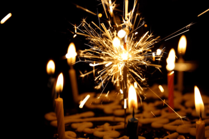 A close up photography of sparkler beside candles on a cake