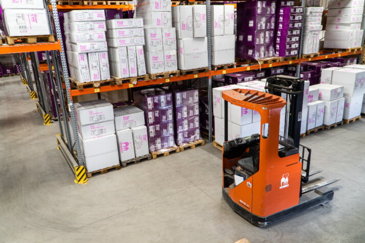 A huge warehouse filled with boxes and a crane next to the shelves.