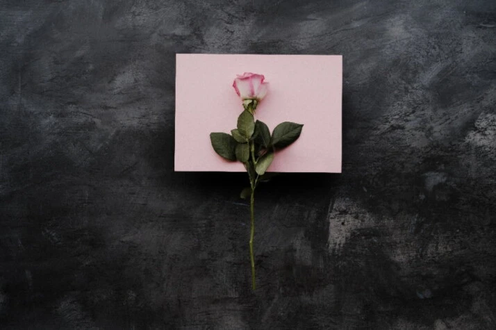A pink love letter with a pink rose on top.