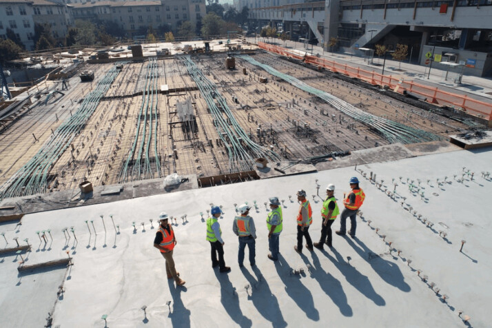 seven construction workers standing on a concrete block admiring the construction.