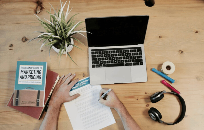 A MacBook Pro near headphones and a marketing book