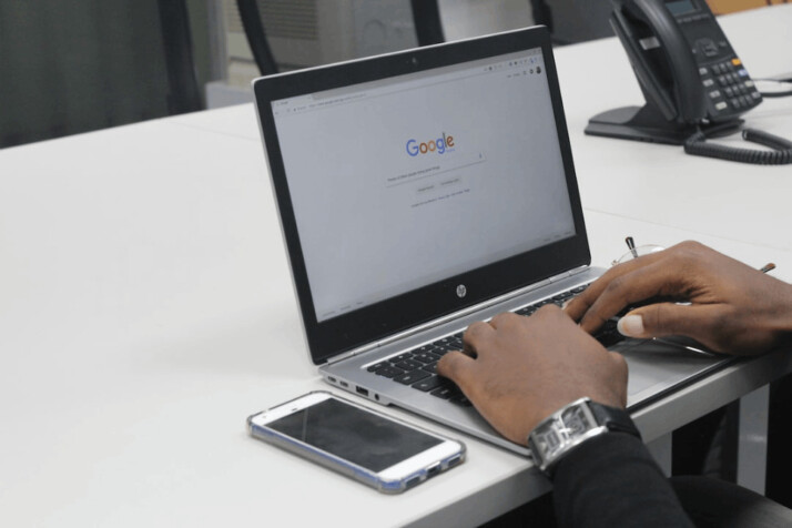 person with wrist watch typing on gray and black HP laptop