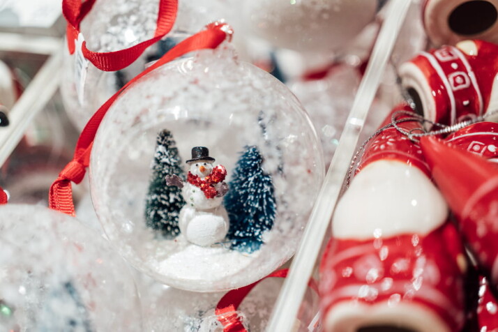 A Christmas ball with a miniature Christmas tree and snowman inside.