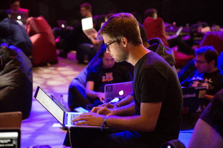 A person working on his laptop along with many others in the background.