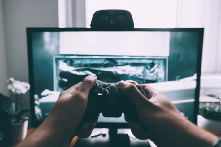 person holding game controller in-front of flat screen television