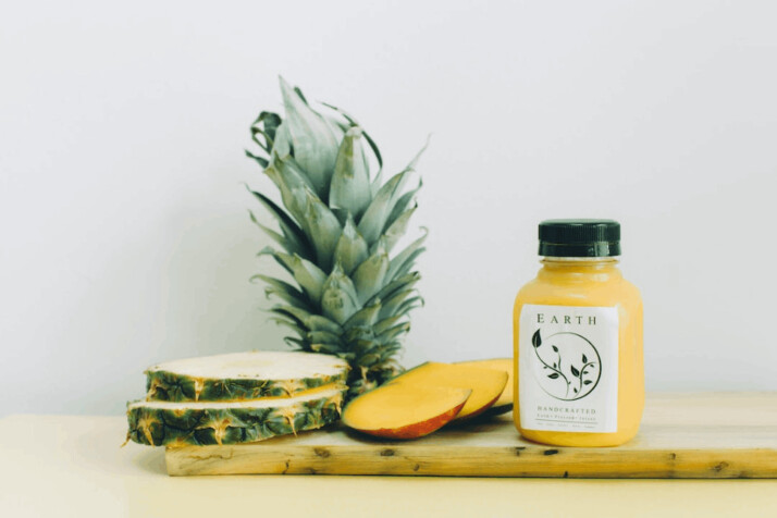 A slice of a pineapple, mango, and earth bottle
