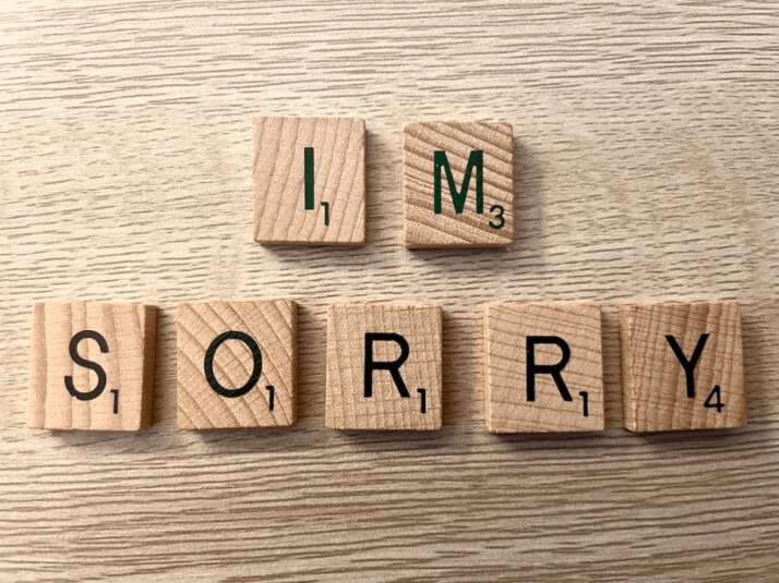 wooden scrabble pieces that spell out I'm Sorry on wooden table.