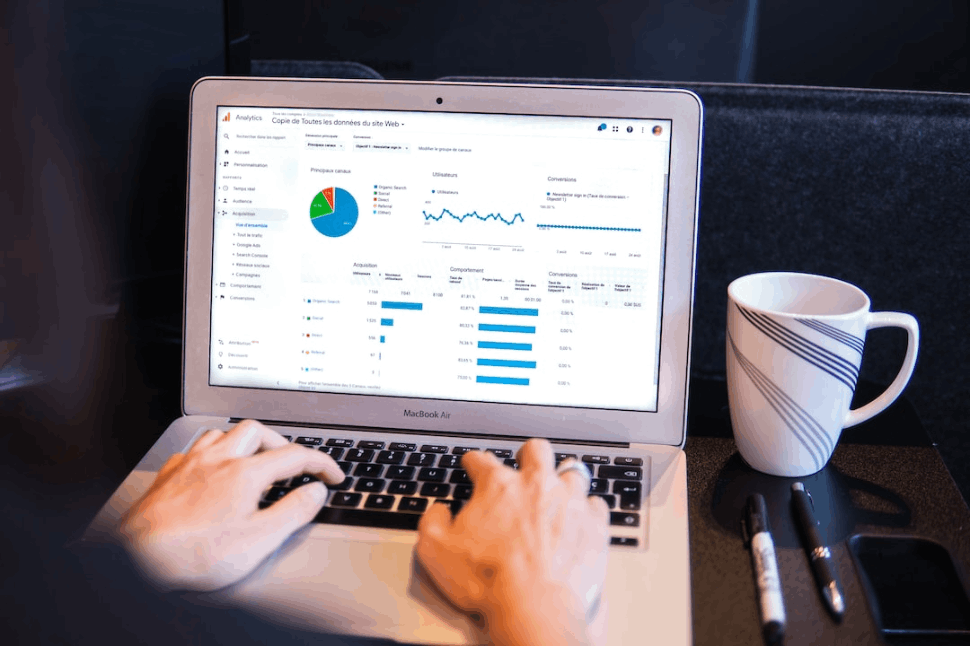 person using macbook pro on black table near white cup