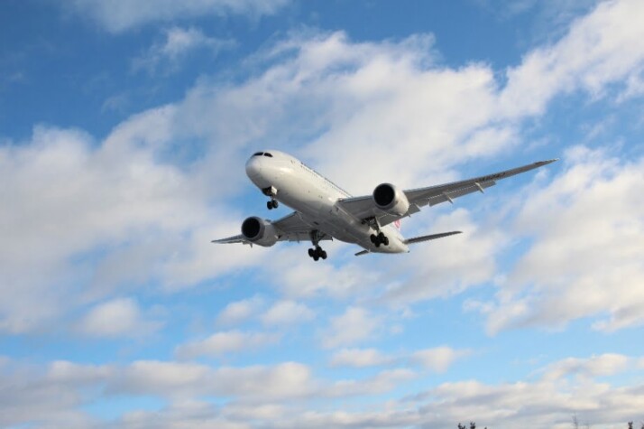 A photo of an airplane flying across the blue sky.