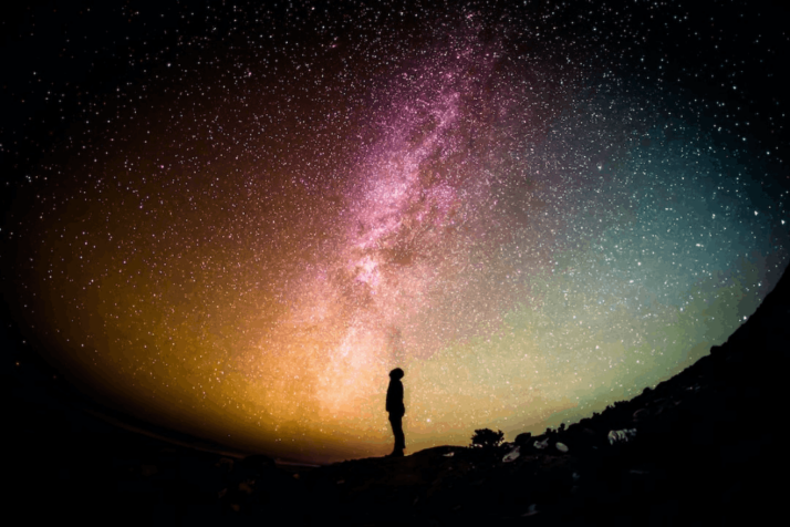 A silhouette photography of a person under a night sky full of stars