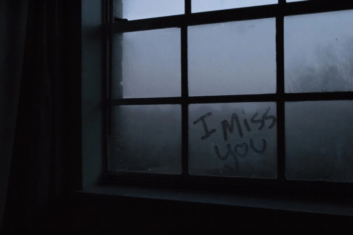 I Miss You text written on a glass window.