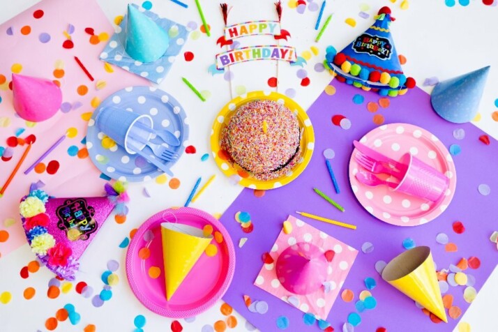 A colorful birthday spread with party hats, confetti, and cake.