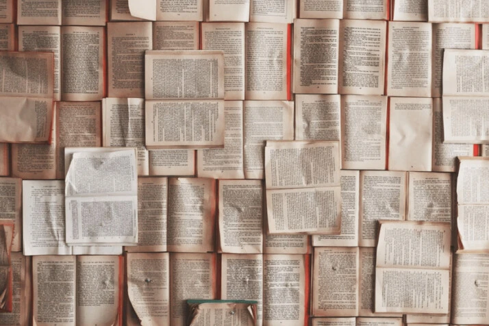a wall filled with books stacked with one another and pinned