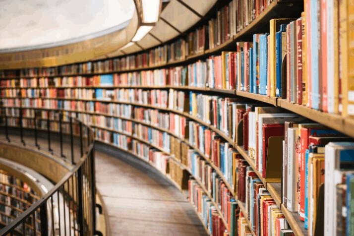 books on brown wooden library shelf in an oval library.