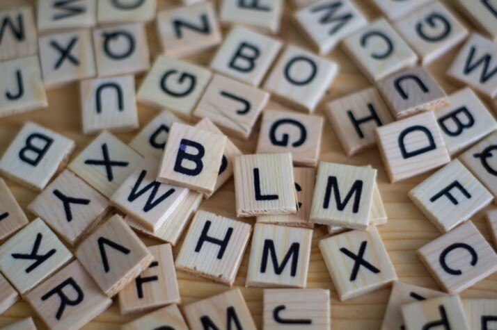 A jumble of random letter tiles made of wood.