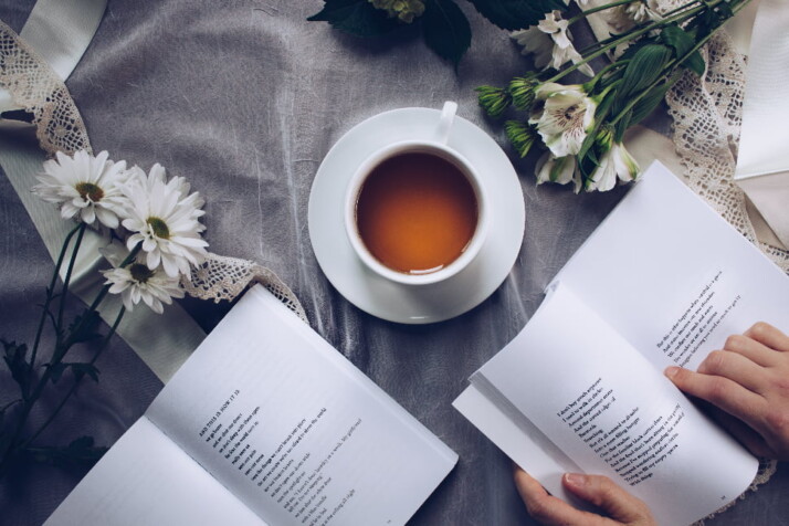 Two open books of poetry placed next to a cup of coffee.