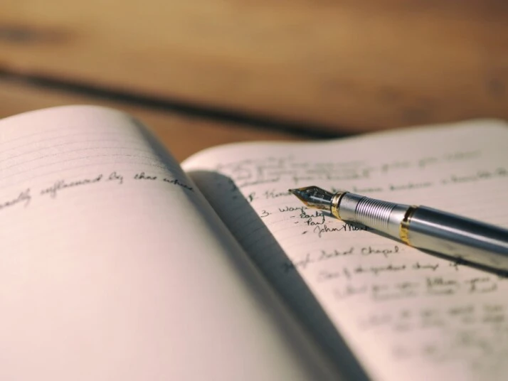 A fountain pen placed on the pages of a notebook.