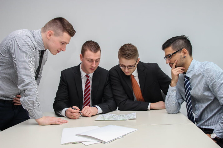 Four men discussing something that's written on a piece of paper.