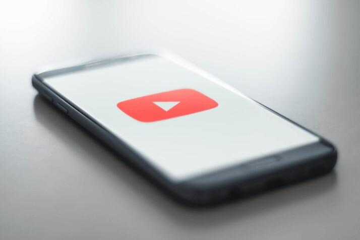 a black smartphone showing the opening logo of YouTube