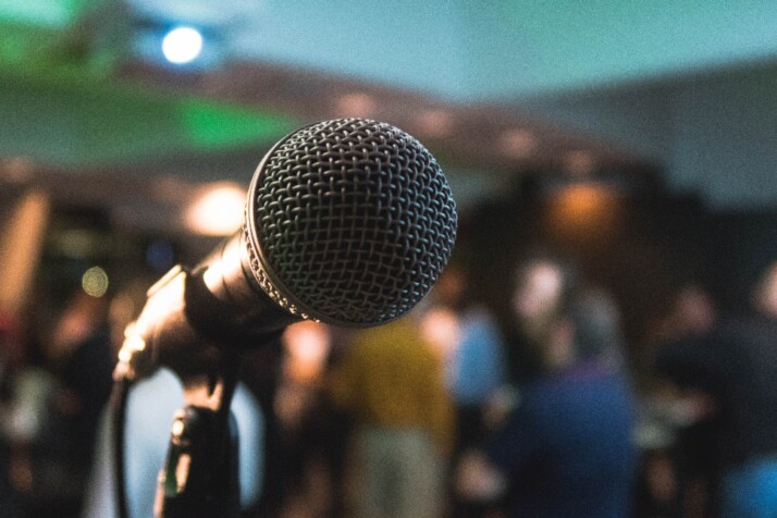 In focus photograph of a microphone with people in the background out of focus