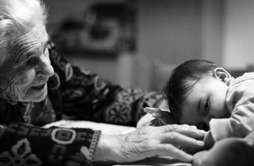 A black and white photo of a little kid and his grandmother.