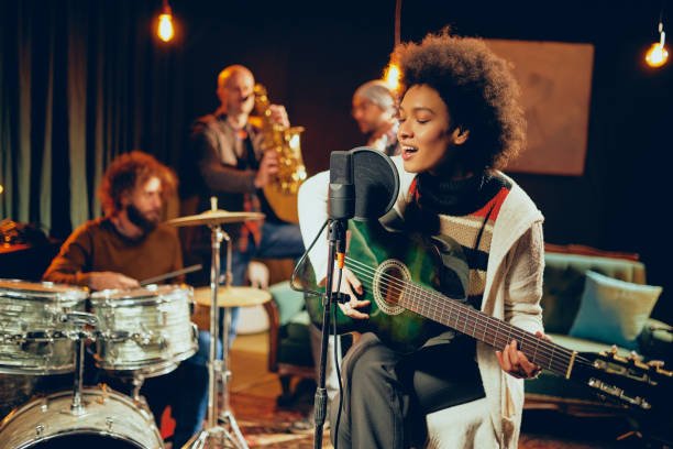 mixed race woman with afro singing and playing guitar picture 
