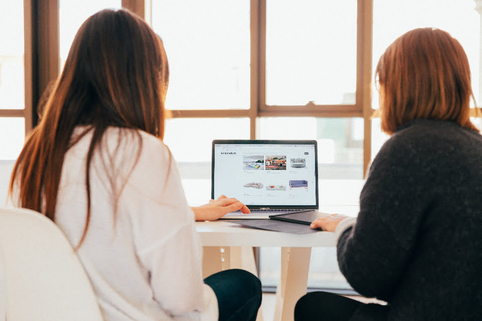 Two women working on something together on a laptop.