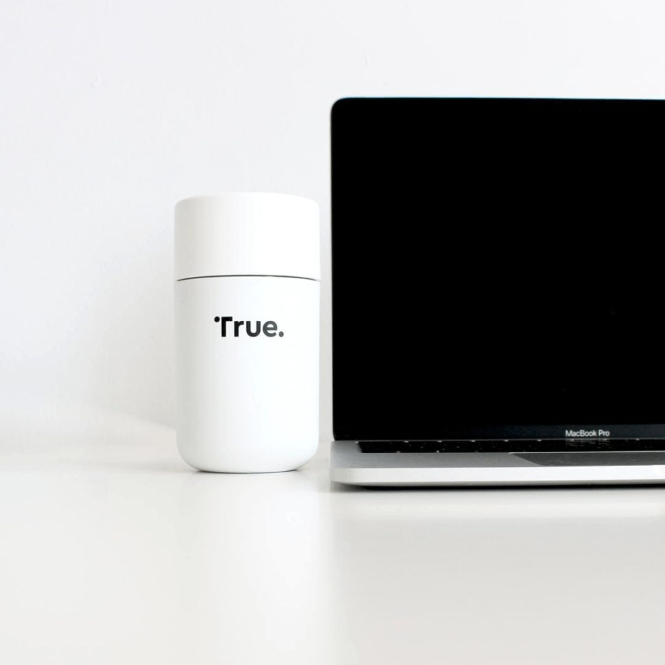 silver MacBook Pro beside an object with 'true' inscribed on it.