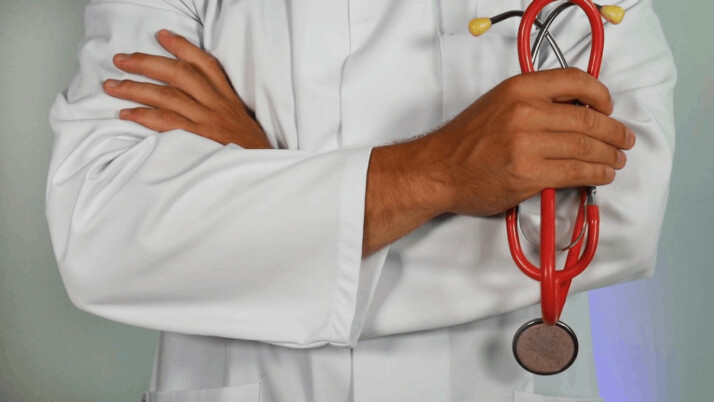 a doctor holding a red stethoscope and wearing a white coat