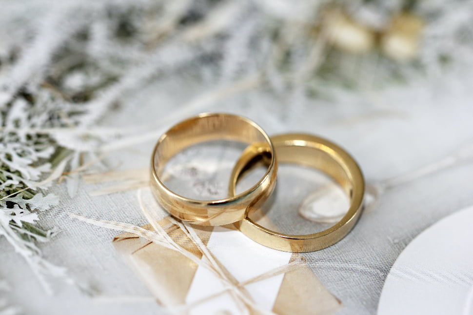 Two gold wedding rings placed on a white surface