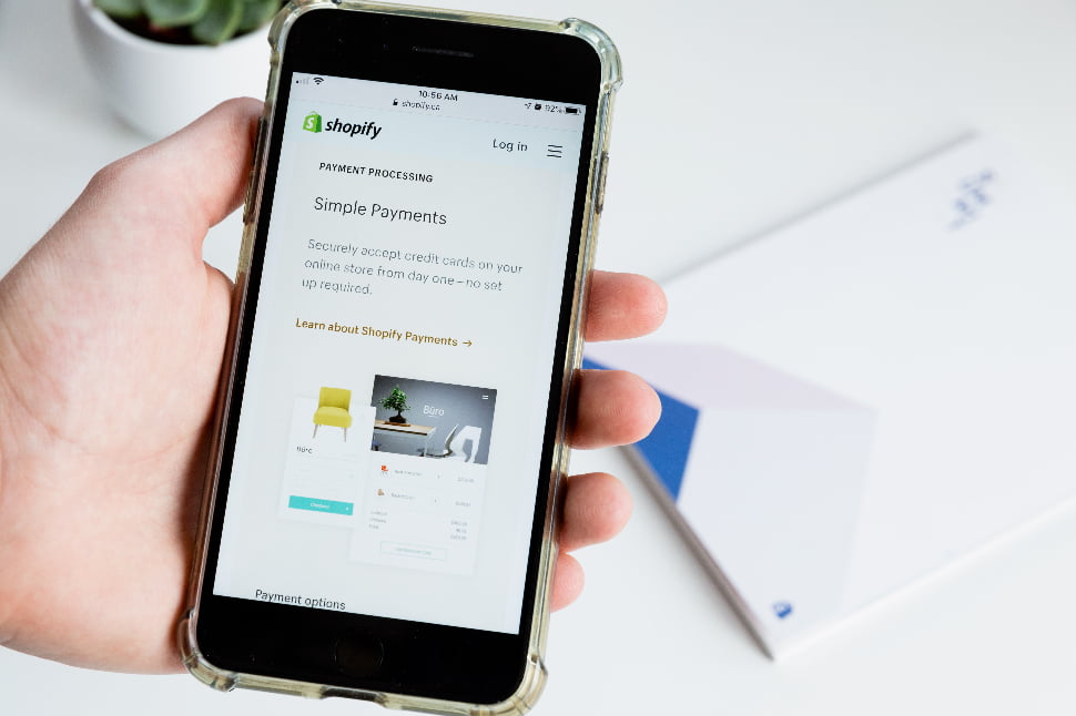 A person holding a phone that's displaying the Shopify payment processing page.