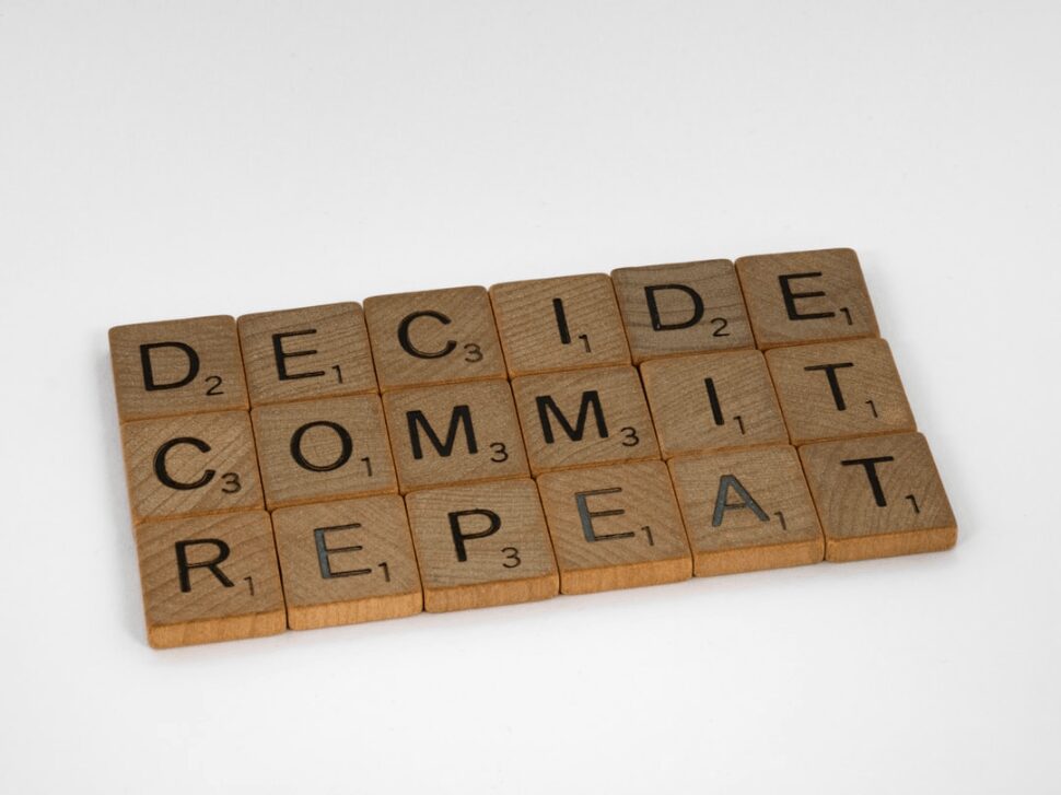 Decide Commit Repeat wooden scrabble blocks on a white surface. 