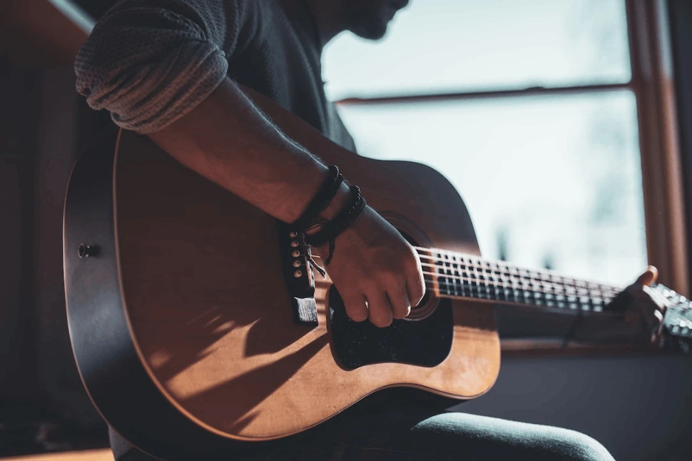 a man playing an acoustic guitar selective focus photography