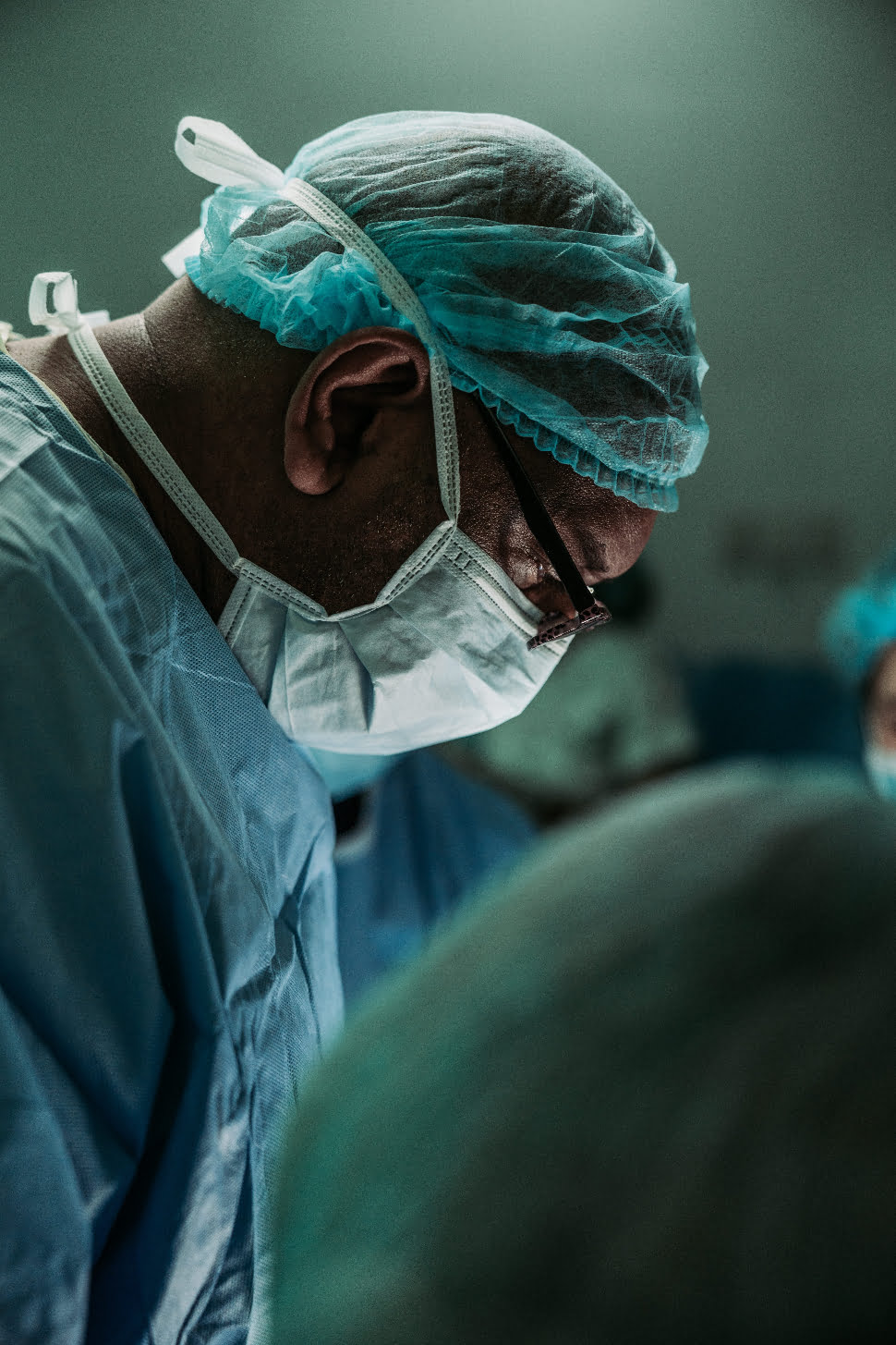 a surgeon in the operating theatre focusing on his patient.