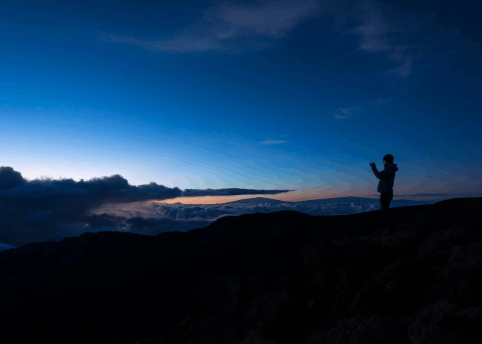 A silhouette of a man taking photo on rock cliff